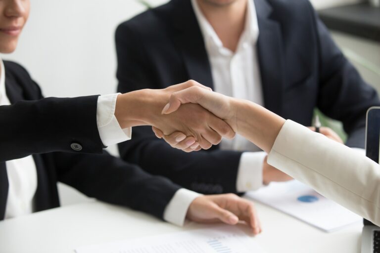 Business owners shaking hands while discussing an acquisition